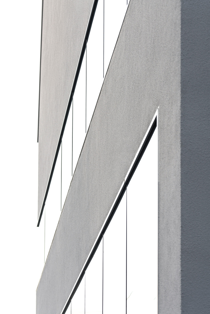 Abstract detail of diagonal shadow lines cutting across the white rendered facade in bright daylight