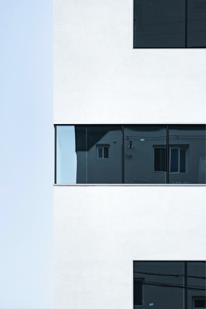 Stacked white volumes with recessed glazed balconies reflecting adjacent residential buildings