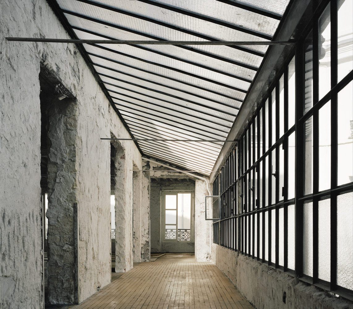 Before: glass-roofed gallery along courtyard wall, stripped to bare masonry