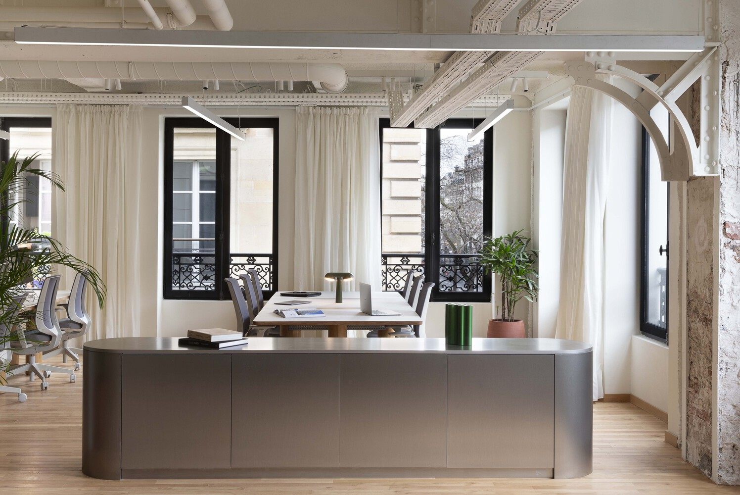After: executive office with grey island desk, French doors to balcony, white curtains, exposed arched beam