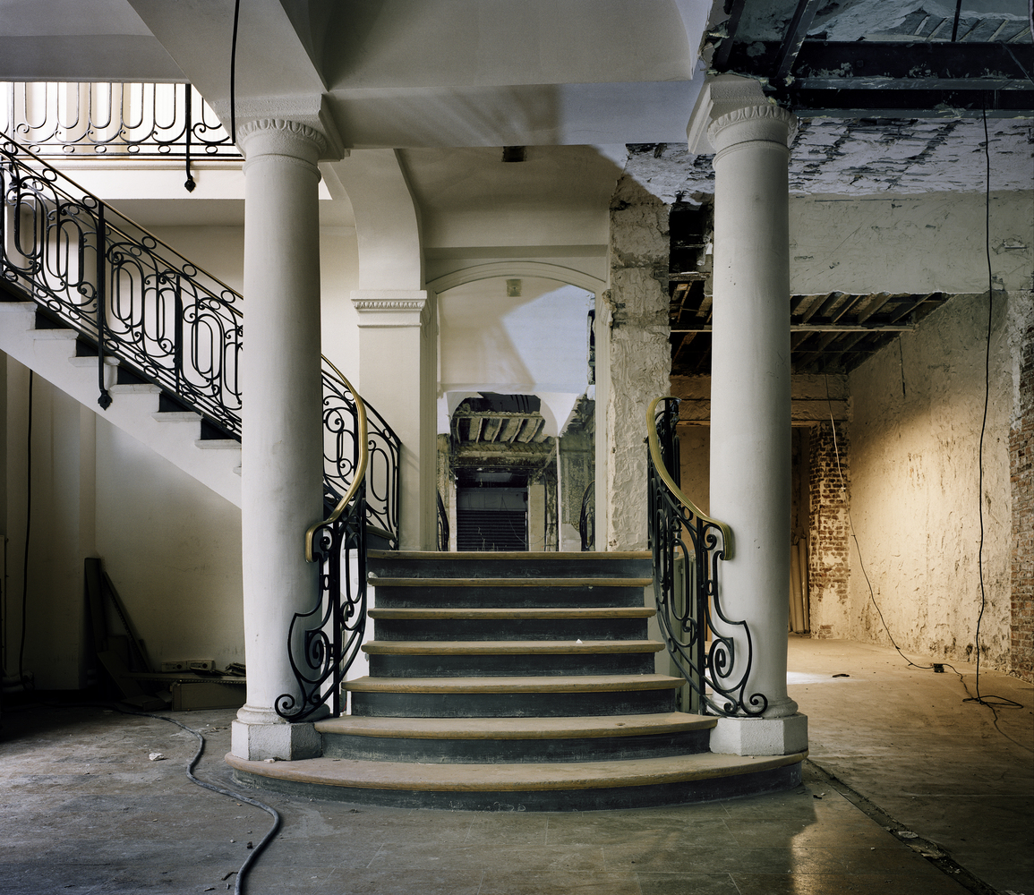 Before: grand entrance staircase with columns, iron railings, worn stone, exposed wiring