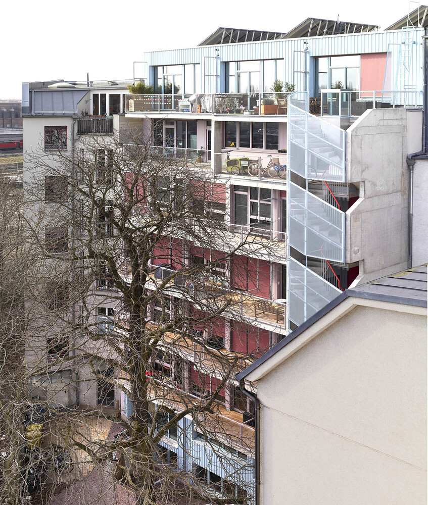 Courtyard elevation revealing multiple residential levels with balconies, bicycles, and planted terraces in winter