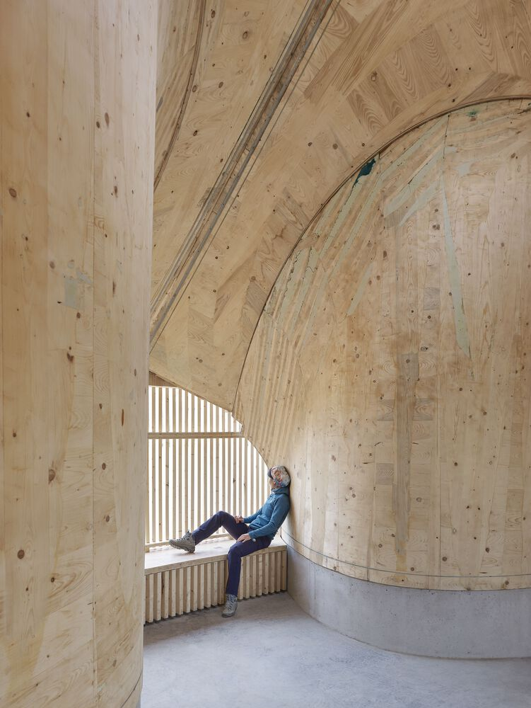 Interior window alcove with timber vault ceiling and seated figure silhouetted against slatted screen