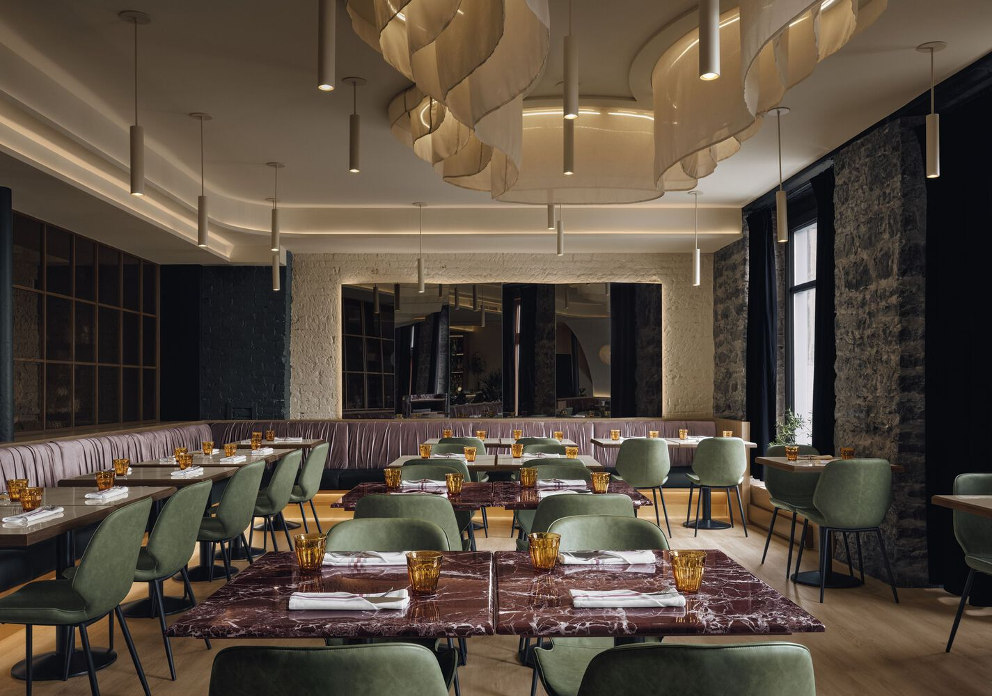 Dining room interior with spiraling layered pendant fixtures and set tables beneath a cove-lit ceiling