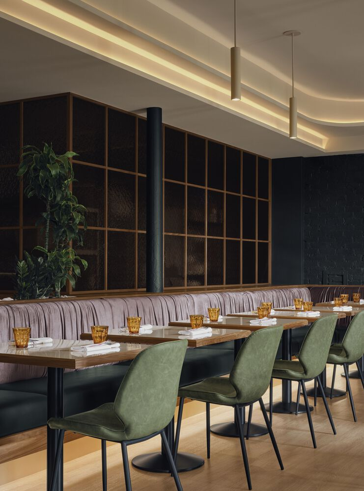 Dining area with timber grid partition, striped banquette seating, and pendant lights under curved ceiling