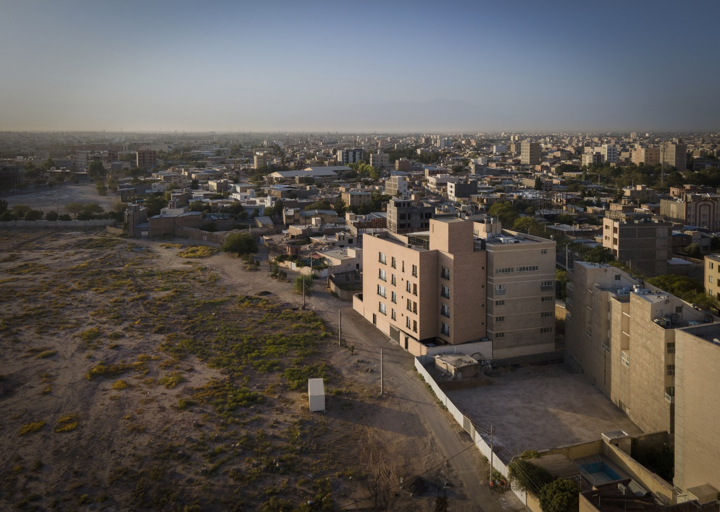 Aerial view of the residential tower among low-rise buildings and vacant land at dusk
