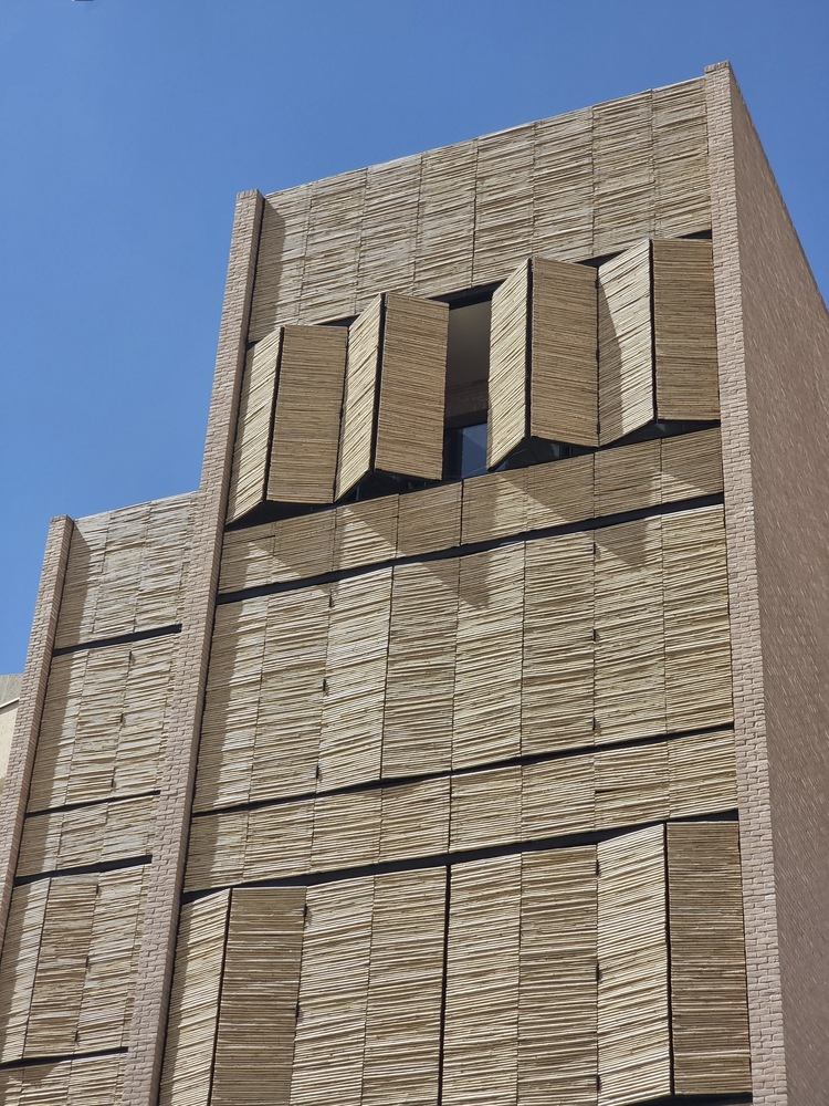 Upper facade with deeply recessed windows set into horizontal courses of textured brick