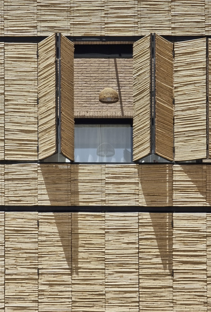 Facade detail showing horizontal reed shutters flanking a glazed opening with visible pendant light inside