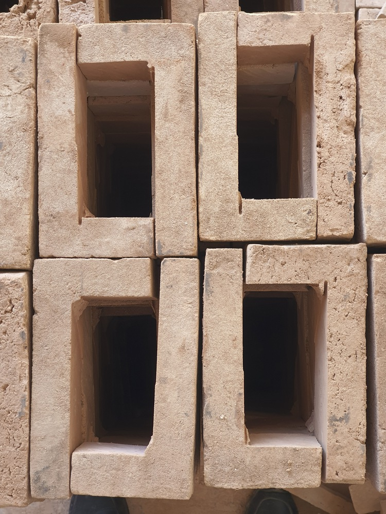 Close-up of precast concrete blocks with recessed openings stacked in an irregular pattern