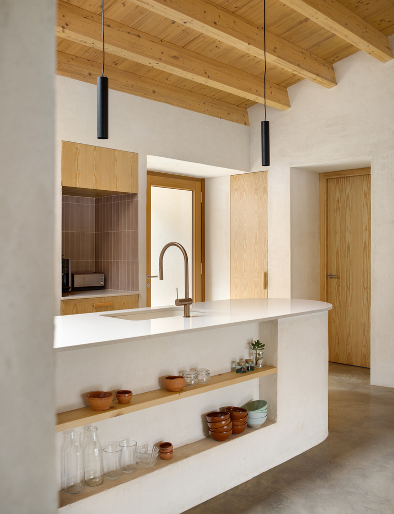 Corridor detail: curved plaster wall meeting concrete floor, timber door glimpsed at the end