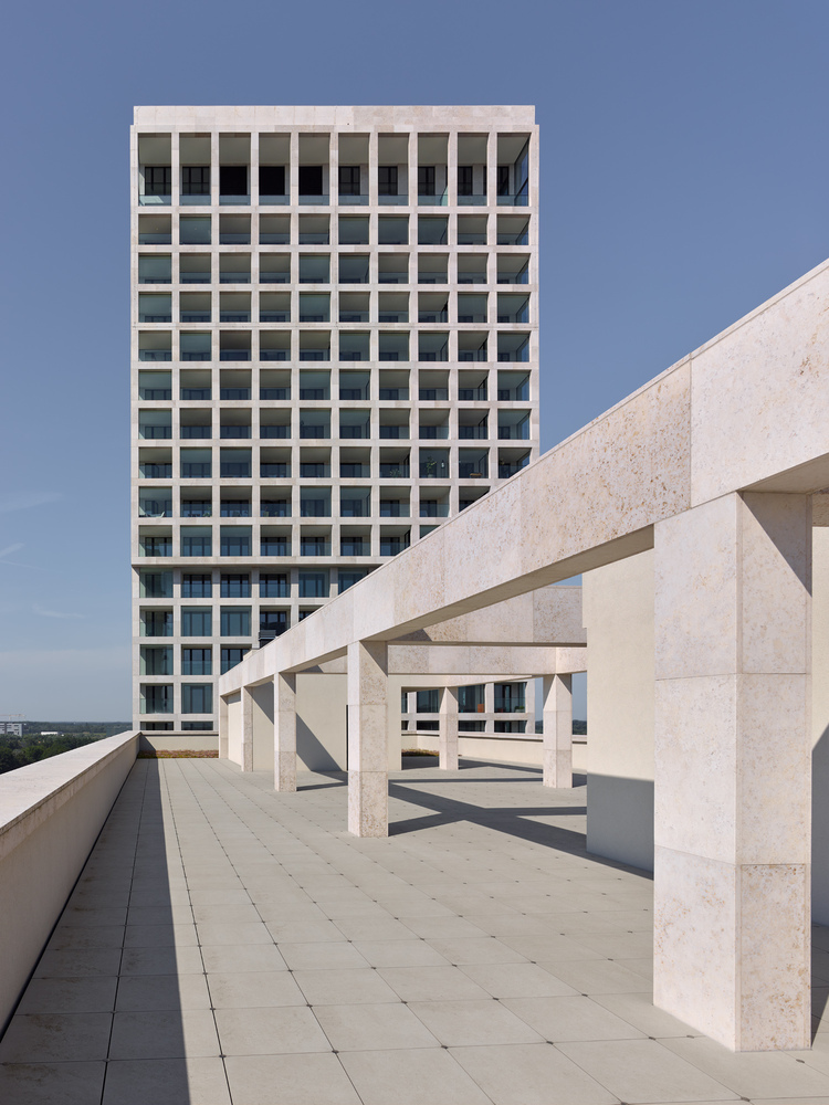 Rooftop terrace with precast concrete pergola structure and tower block visible beyond under clear sky