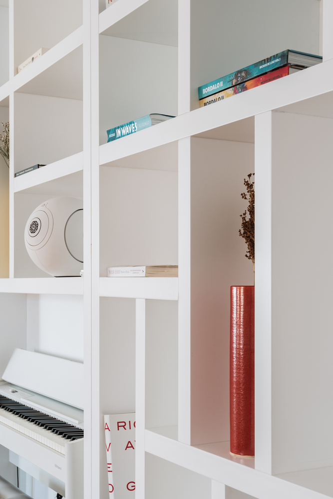 Detail of white shelving compartments displaying books and ceramic objects