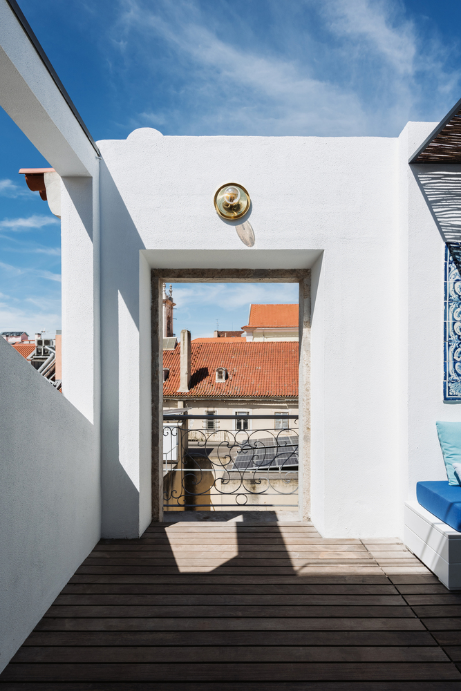 Rooftop terrace with timber decking framing a view of orange-tiled rooftops beneath clear blue sky