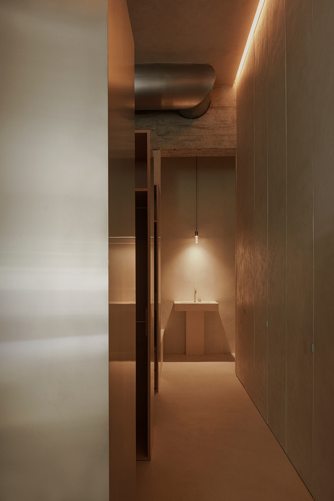 Corridor view toward a stepped altar-like platform illuminated by a single pendant light
