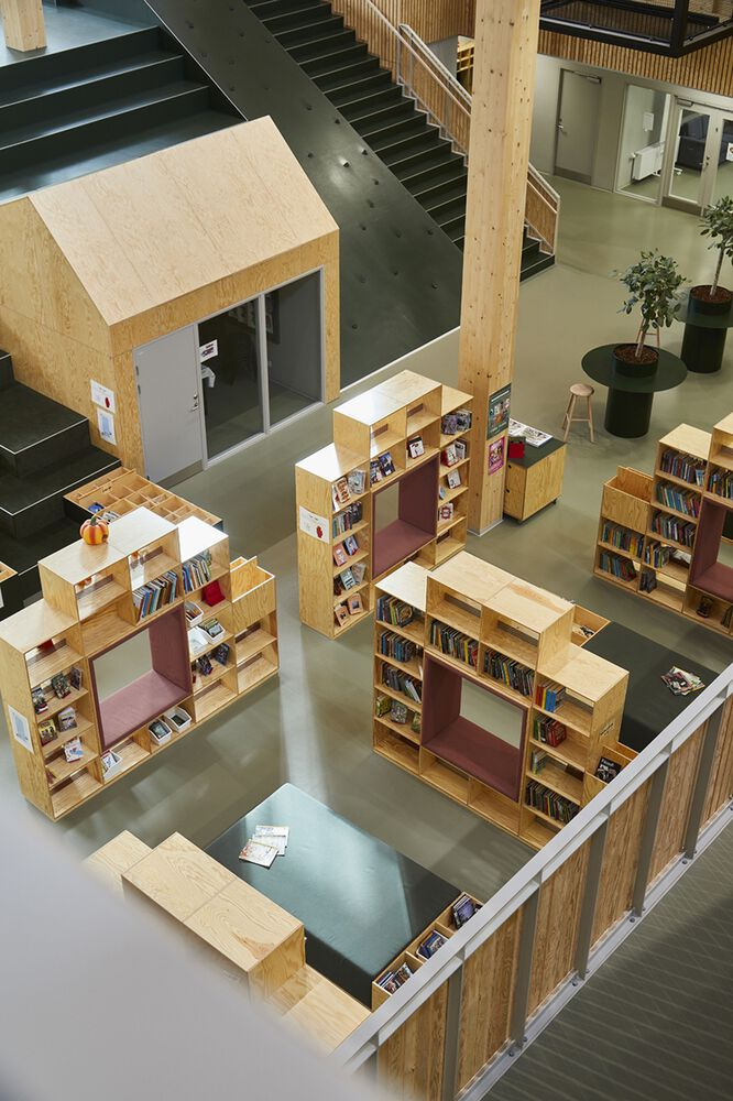 Core space interior: three-storey timber atrium with green stepped seating hill, clerestory light, timber columns and beams