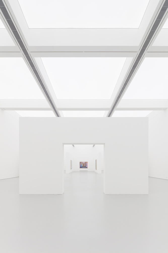 Enfilade: deep perspective through aligned white openings, luminous ceiling panels above, a single small painting at the far end