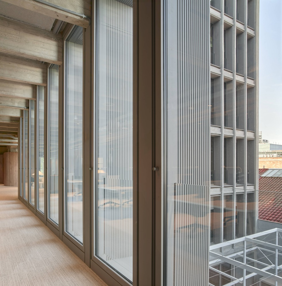 Furniture detail: round timber table, upholstered chairs, floor lamp, vertical louvres behind