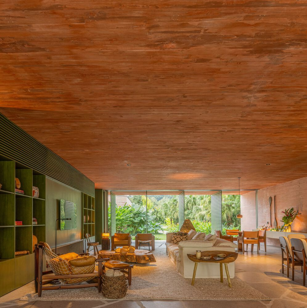 Living space with timber plank ceiling and perforated metal screens opening to garden in afternoon light