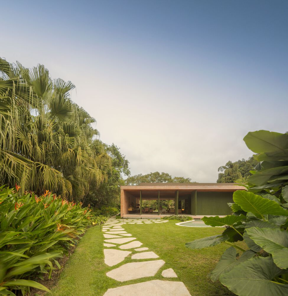 Flat-roofed pavilion set in a tropical garden with curved stepping stones and palm trees
