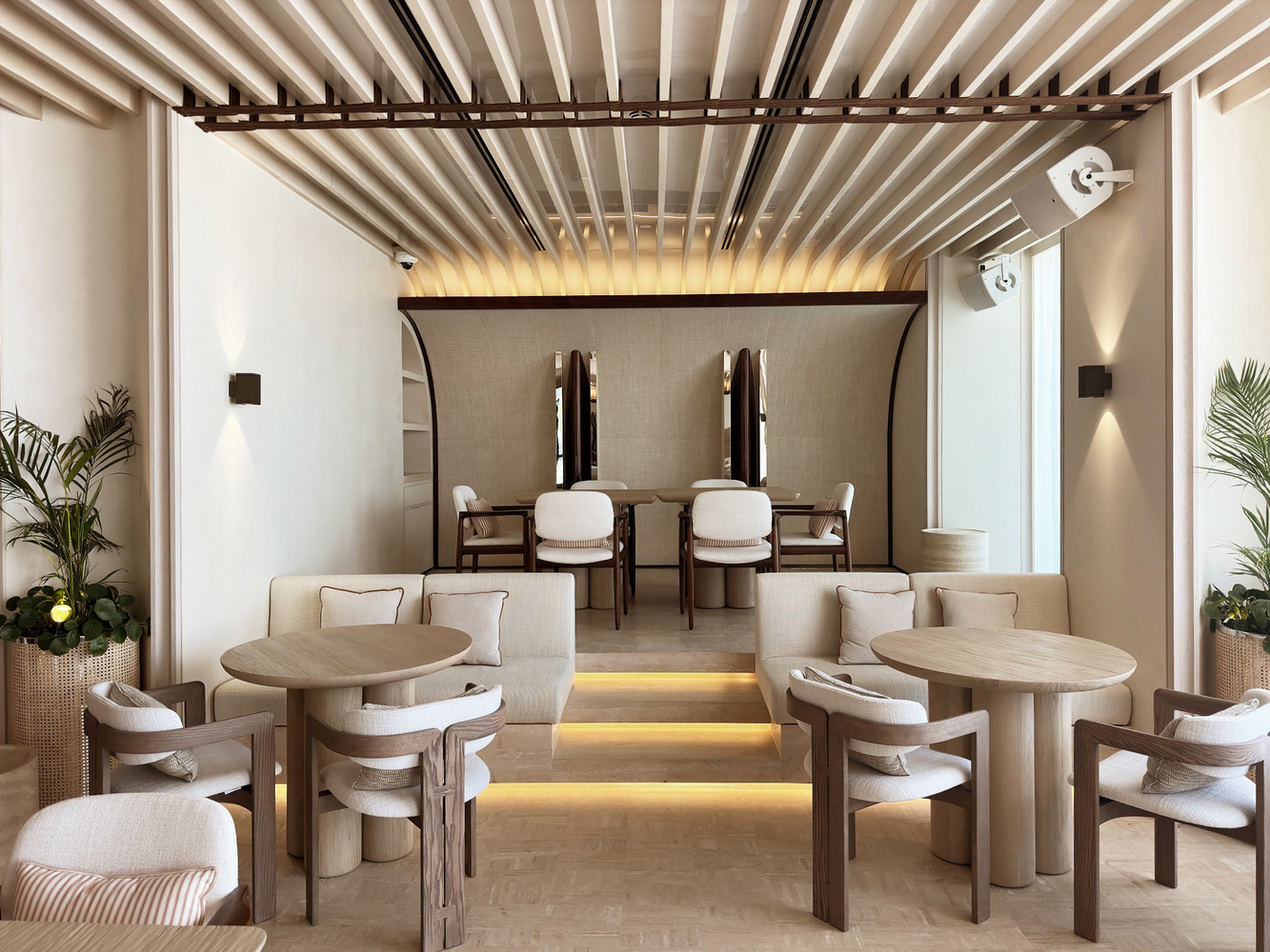 Ilios ground floor: white arched ceiling with timber slat canopy, elevated seating, warm uplighting