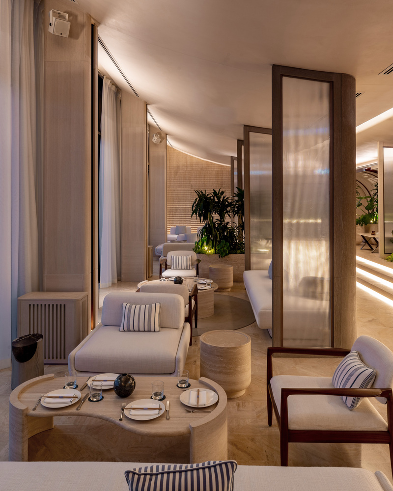 Ilios lounge: curtained alcove seating, low tables, curved ceiling forms, evening atmosphere