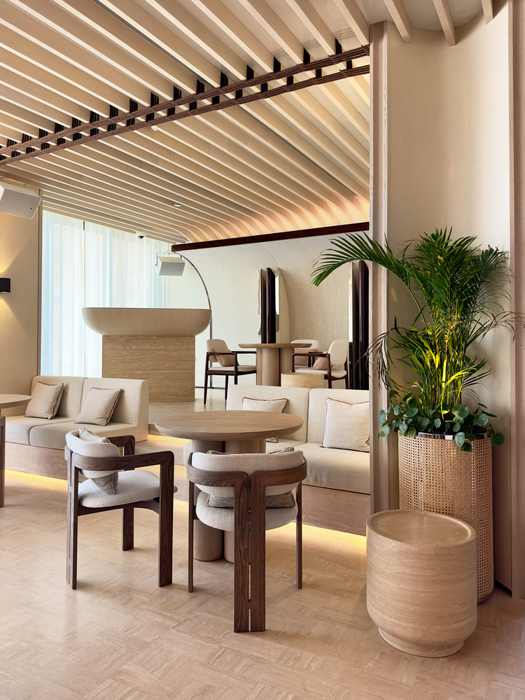 Ilios dining: timber slat ceiling, tall mirrors, round tables, palm planter, neutral palette