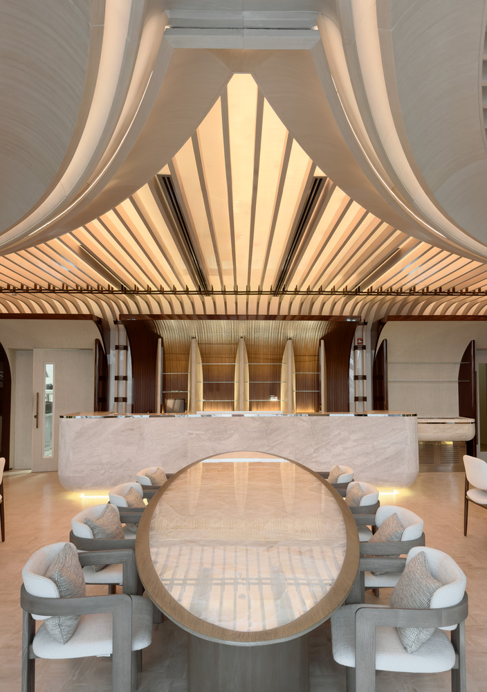Nalu upper floor: dramatic folded ceiling converging to a central peak, white seating, marble bar below