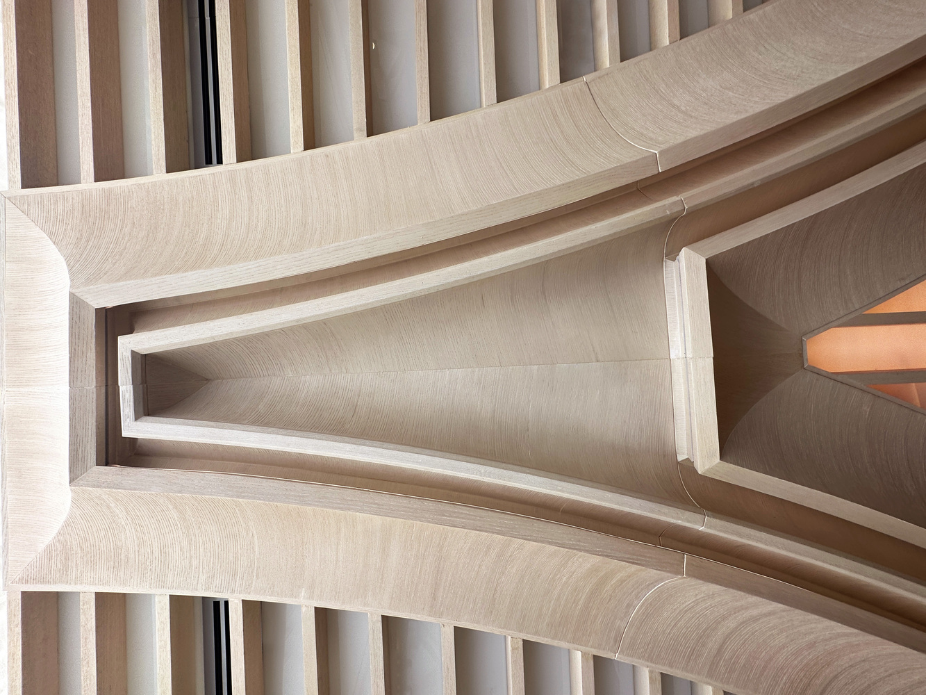 Column detail: looking up at the junction of arched concrete ribs and timber slat ceiling