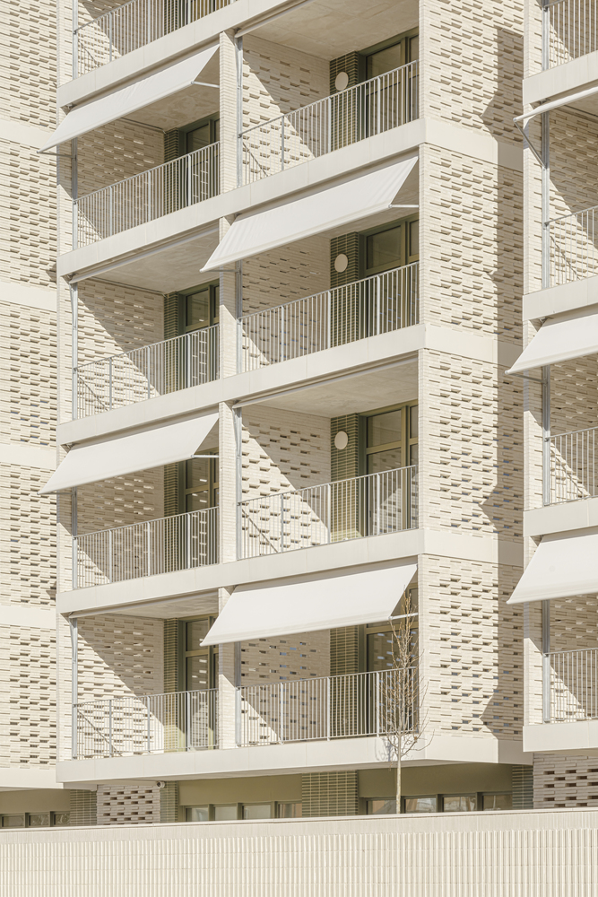 Balcony detail: folding triangular awnings on each balcony, cream brick piers, ceramic brise-soleil panels between windows