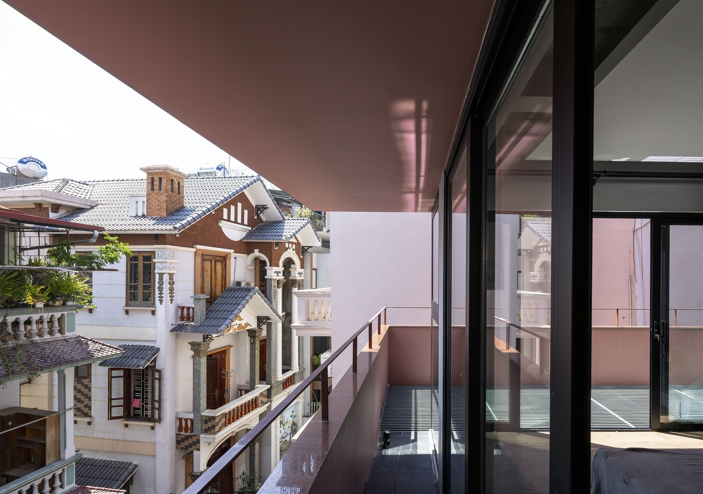 Cantilevered balcony with glass balustrade overlooking traditional pitched-roof houses in afternoon light