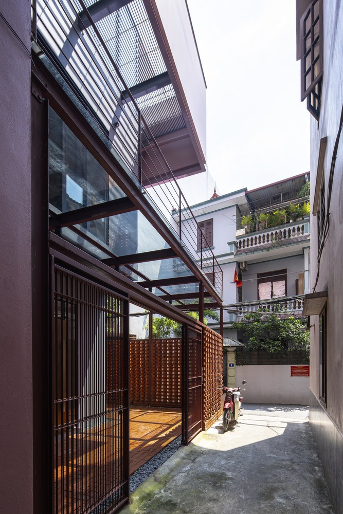 Steel and glass canopy extending over a timber-screened entrance with a motorbike parked beyond