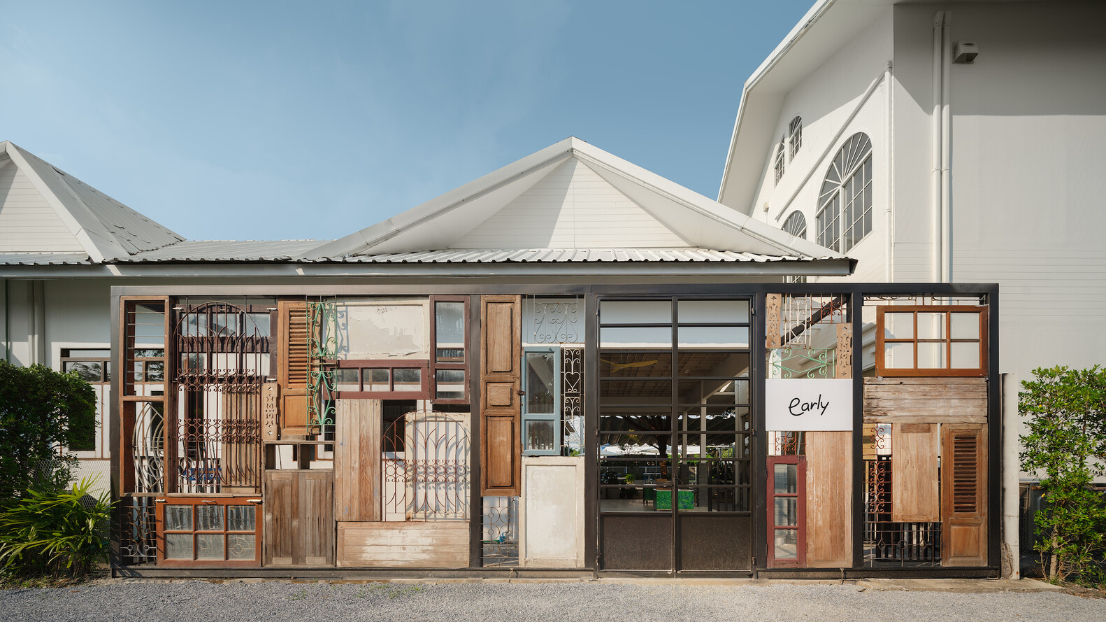 Street facade: salvaged doors, windows, shutters, and iron grilles composed into a patchwork wall