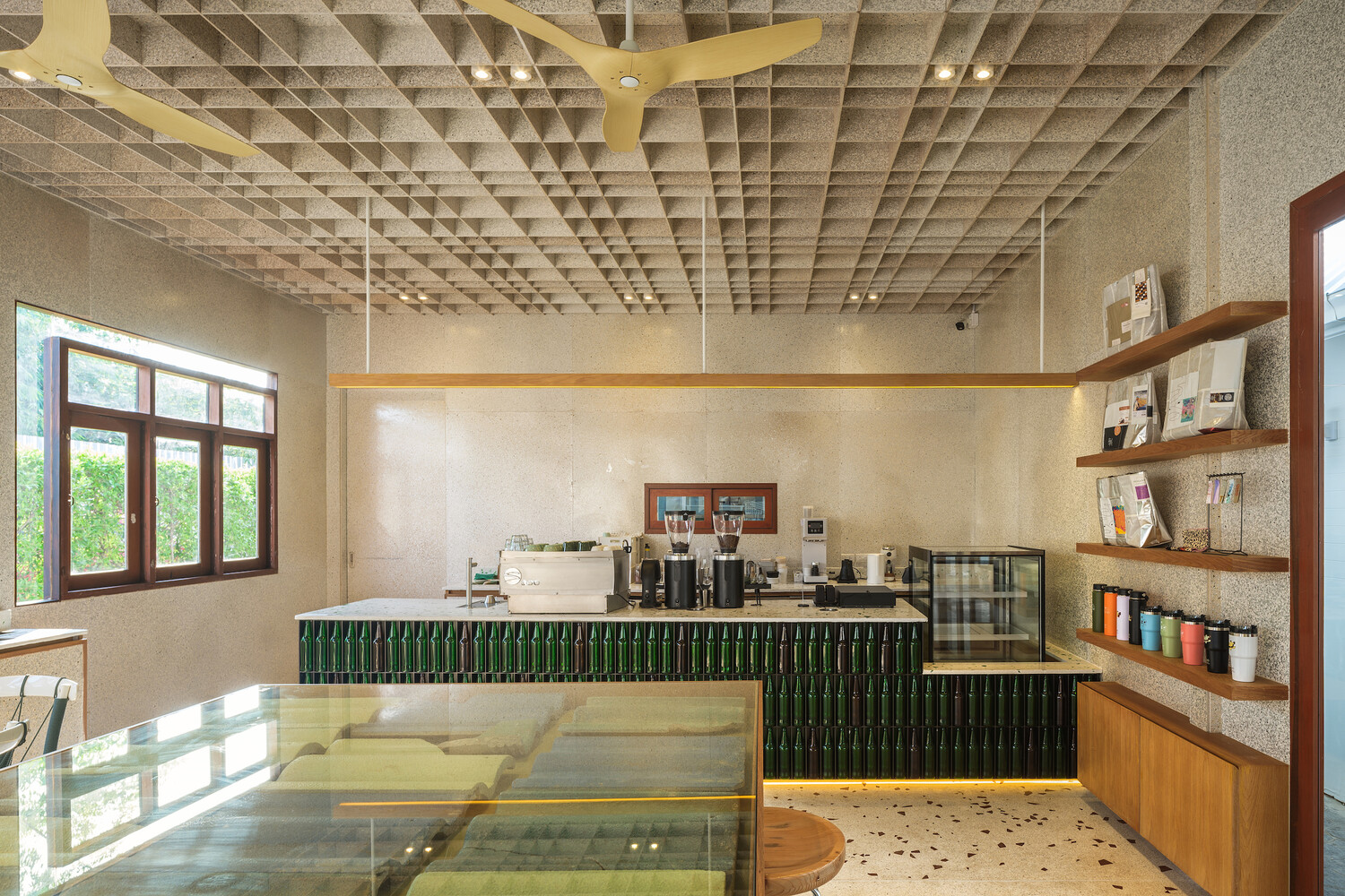 Counter interior: green bottle bar front, terrazzo countertop with glass shards, waffle ceiling, timber shelves