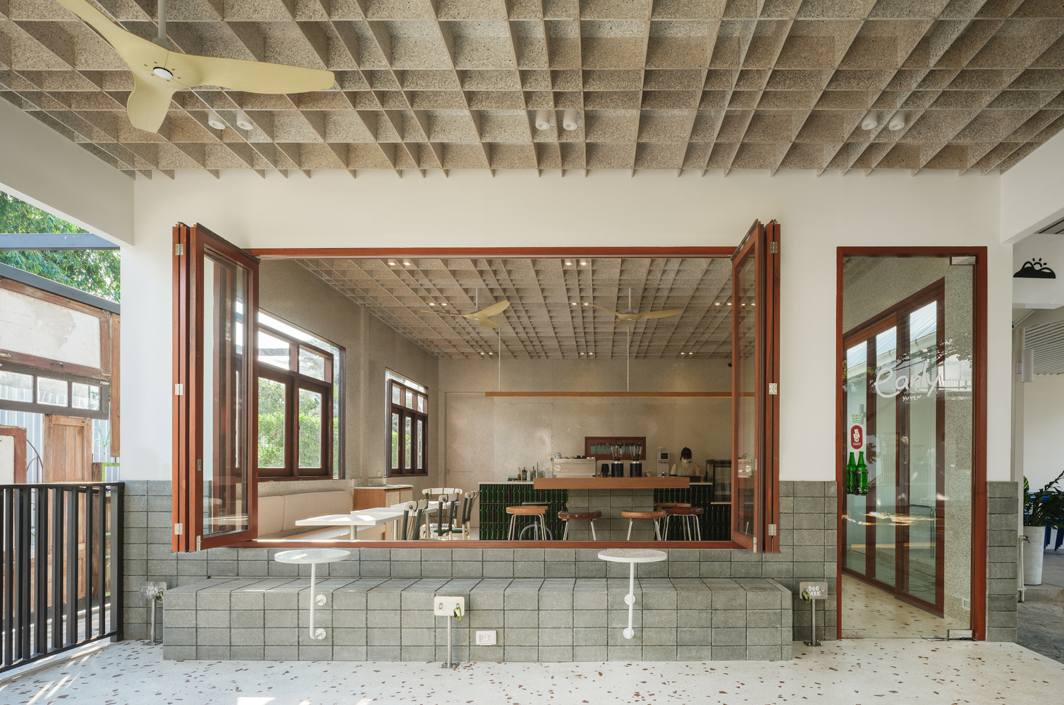 View through folding timber doors: the counter, bar stools, and waffle ceiling from the covered terrace