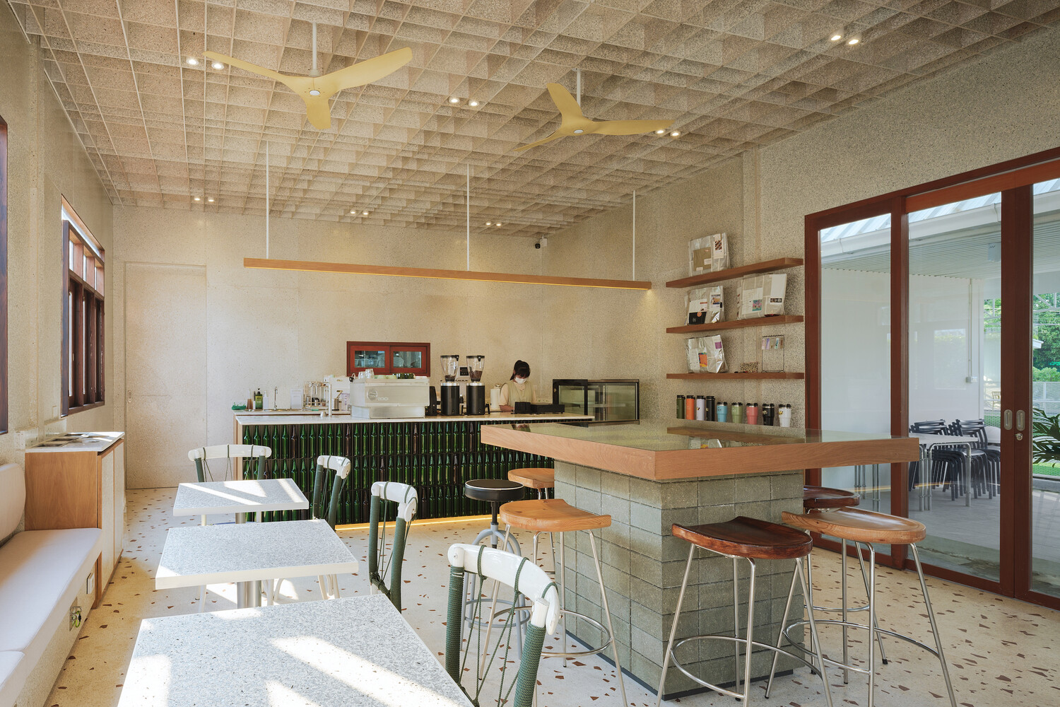 Interior from the bar: tables, metal chairs, salvaged timber windows admitting soft light