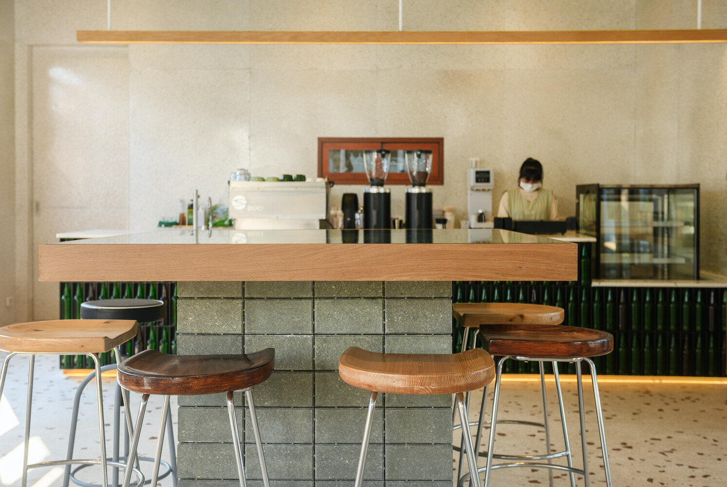 Bar seating: timber-topped stools at the counter, barista working behind, waffle ceiling above
