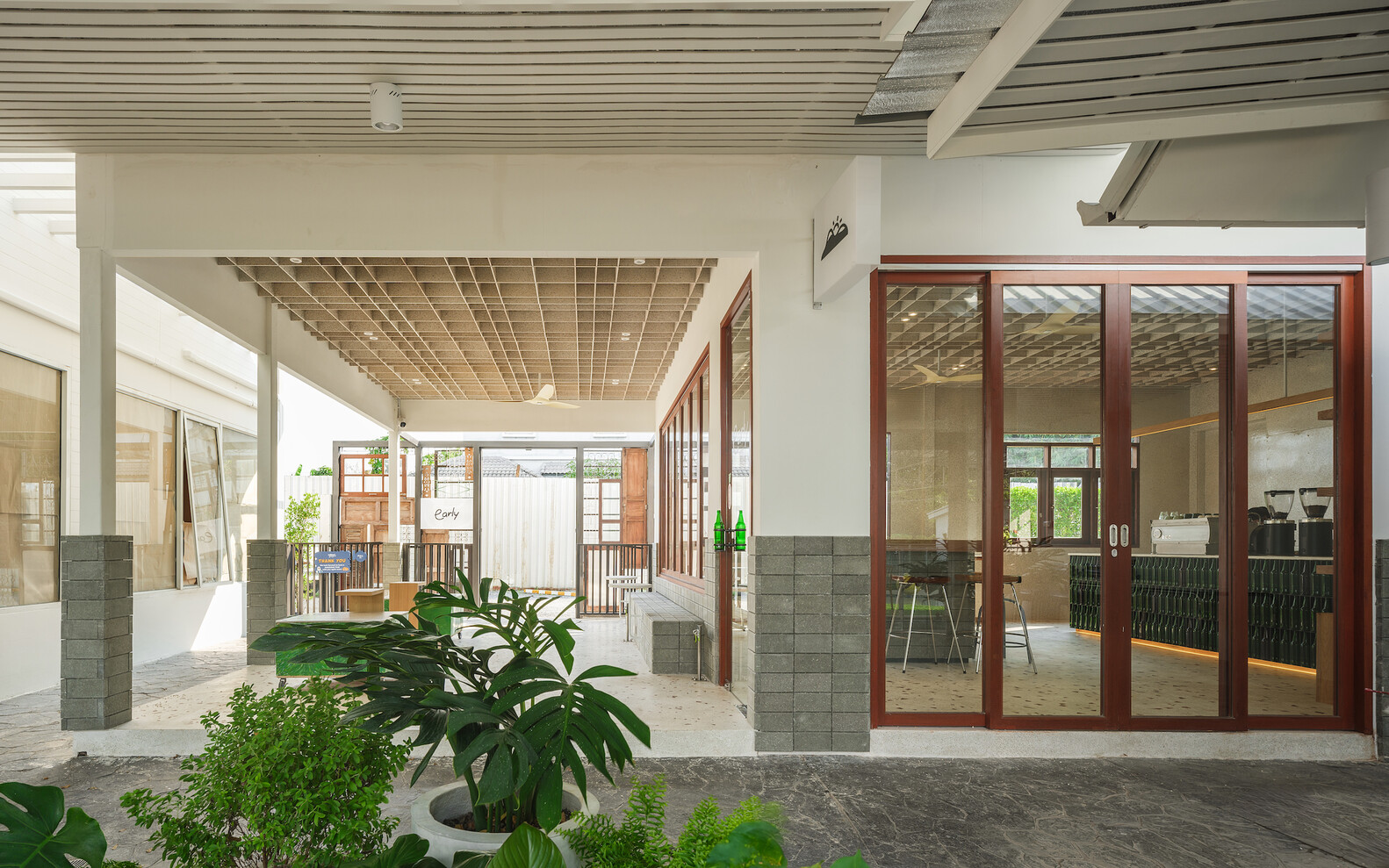 Covered walkway: white columns, reclaimed timber doors to the interior, corrugated and tile roof layers