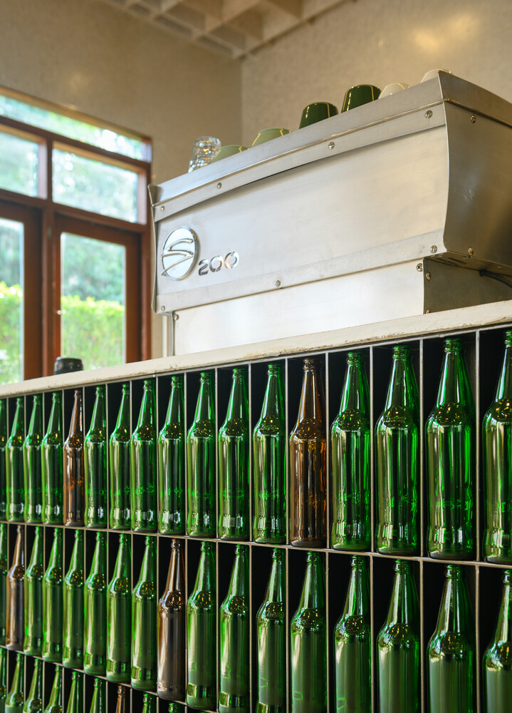 Detail: green glass bottles inverted as bar cladding, terrazzo countertop with embedded glass fragments