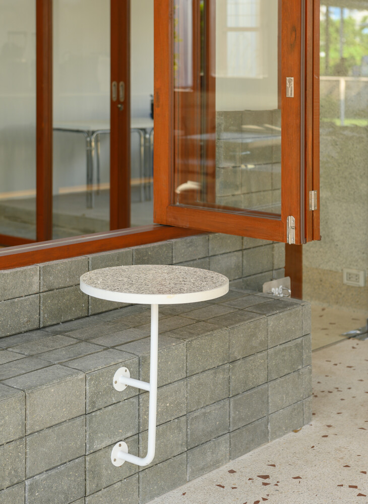 Outdoor step seat: small round white table on a steel bracket, concrete block base, folding door behind