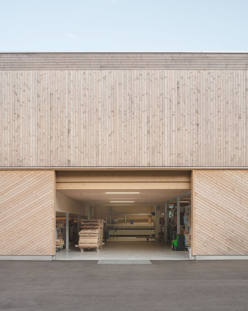 Central garage opening flanked by chevron-patterned timber doors beneath a vertical wood plank facade