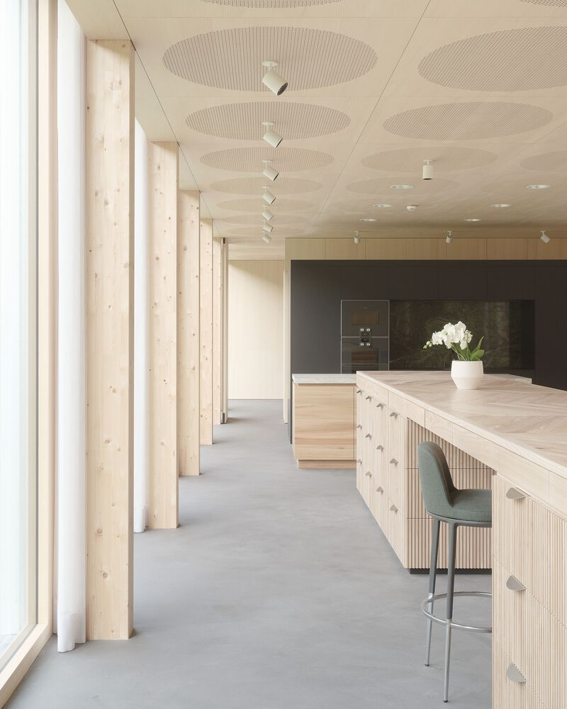 Interior kitchen island with fluted timber base and pale timber columns framing the glazed facade