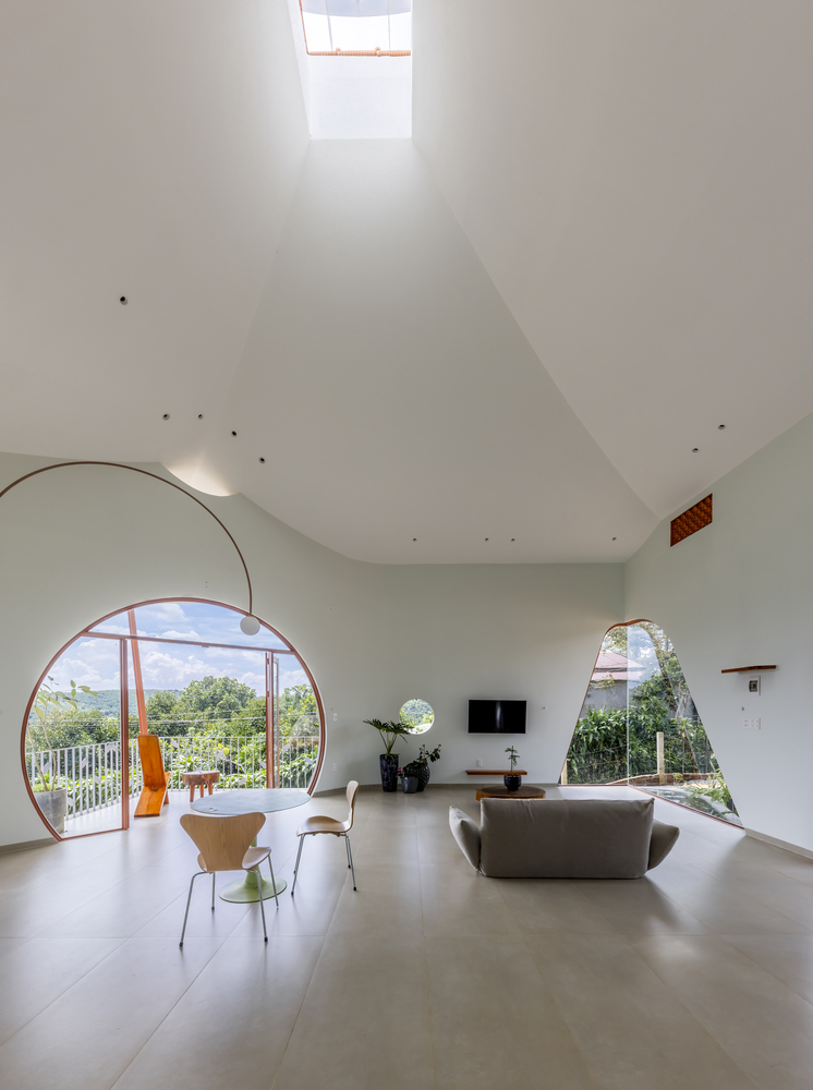 Living room with vaulted white ceiling, large arched windows and skylight overhead flooding the space with daylight