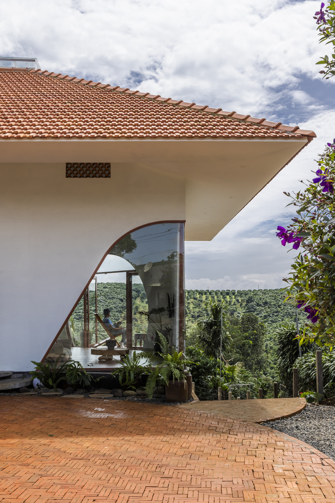 Arched glass opening overlooking distant plantations with herringbone brick terrace and flowering plants