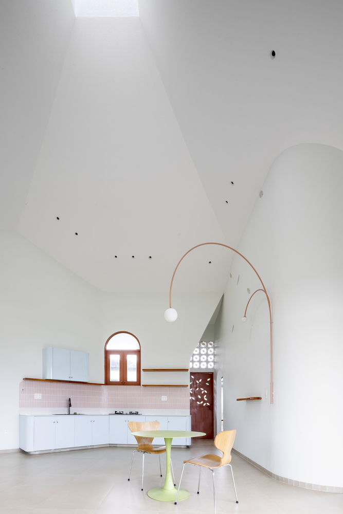 Open-plan kitchen and dining area with vaulted white ceiling and copper pendant lamp