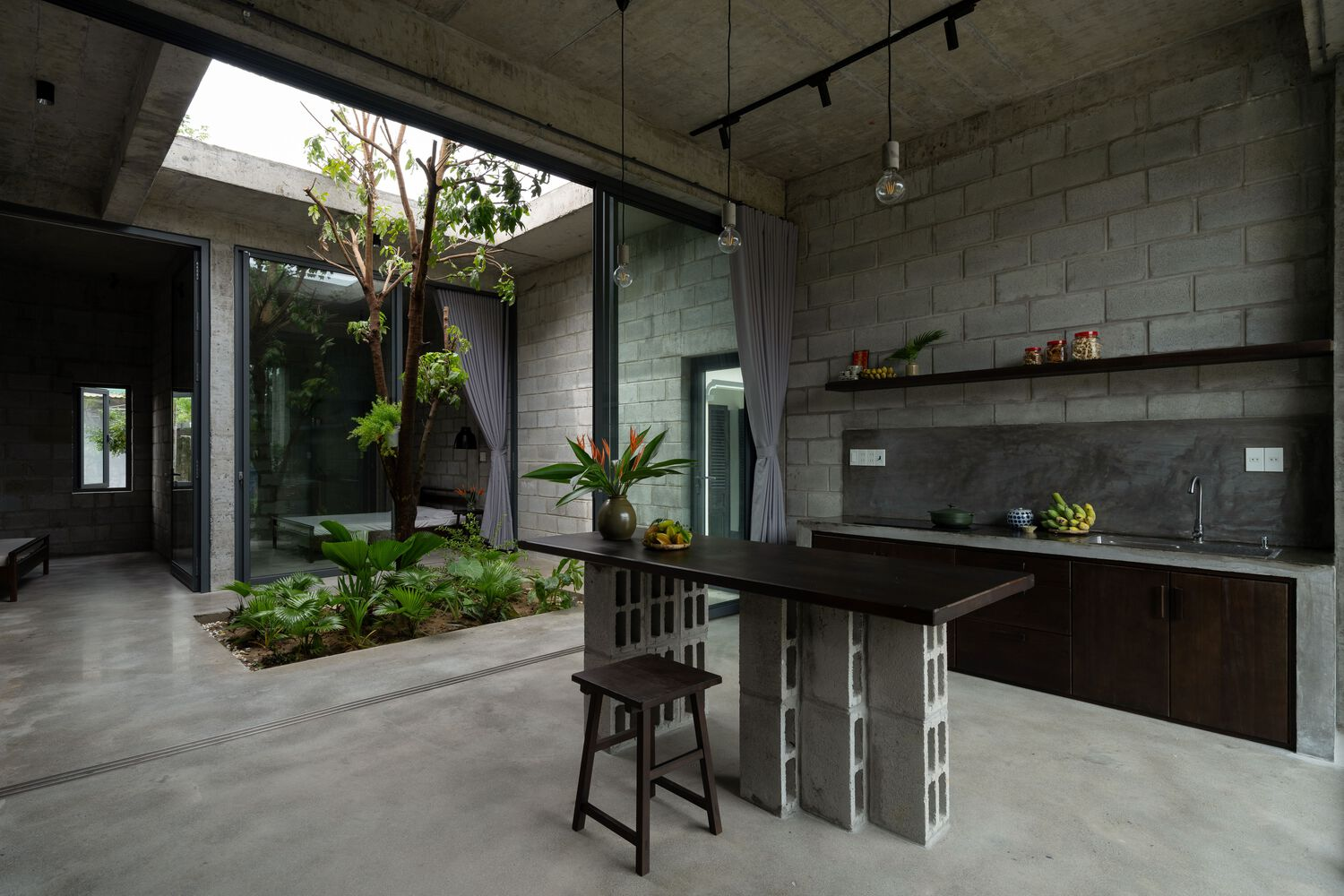 Open-air kitchen with concrete block walls and an internal courtyard garden with tropical plants
