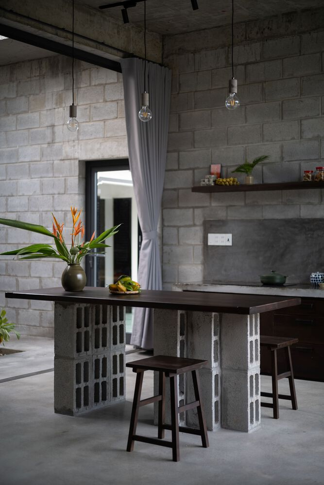 Kitchen island built from stacked concrete blocks with pendant lights hanging above dark timber stools