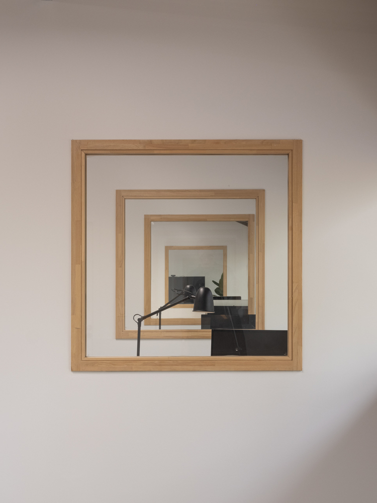 Interior wall opening with nested timber frames revealing a black staircase through layered portals