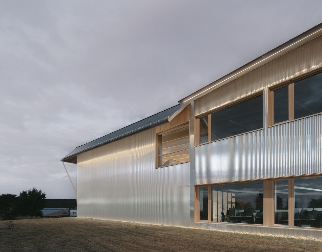 Exterior view showing the angled support columns beneath the overhanging upper floor at twilight
