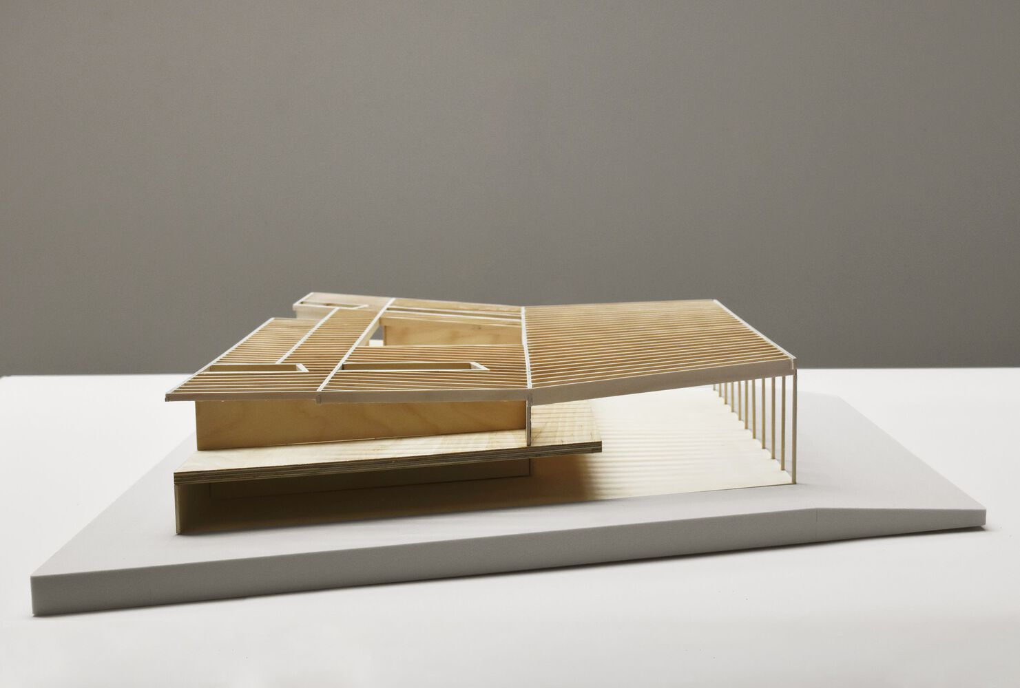Physical model viewed from the corner revealing colonnade and folded roof planes in wood and acrylic