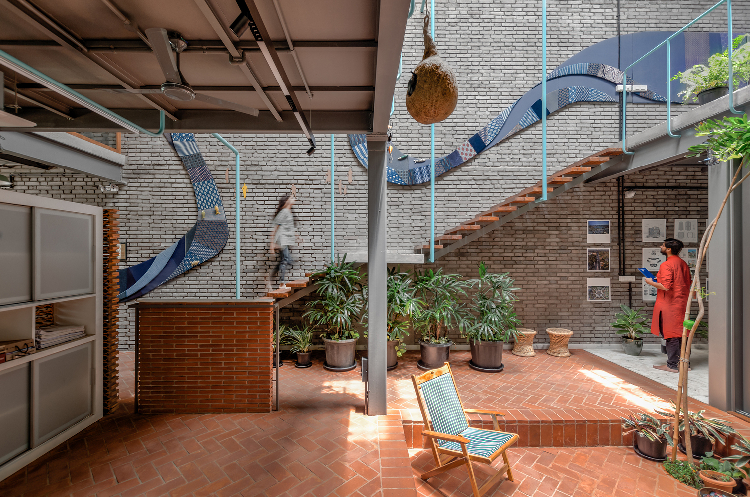 Interior courtyard with terracotta tile floor, metal slide installation, and brick walls beneath an exposed rafter ceiling